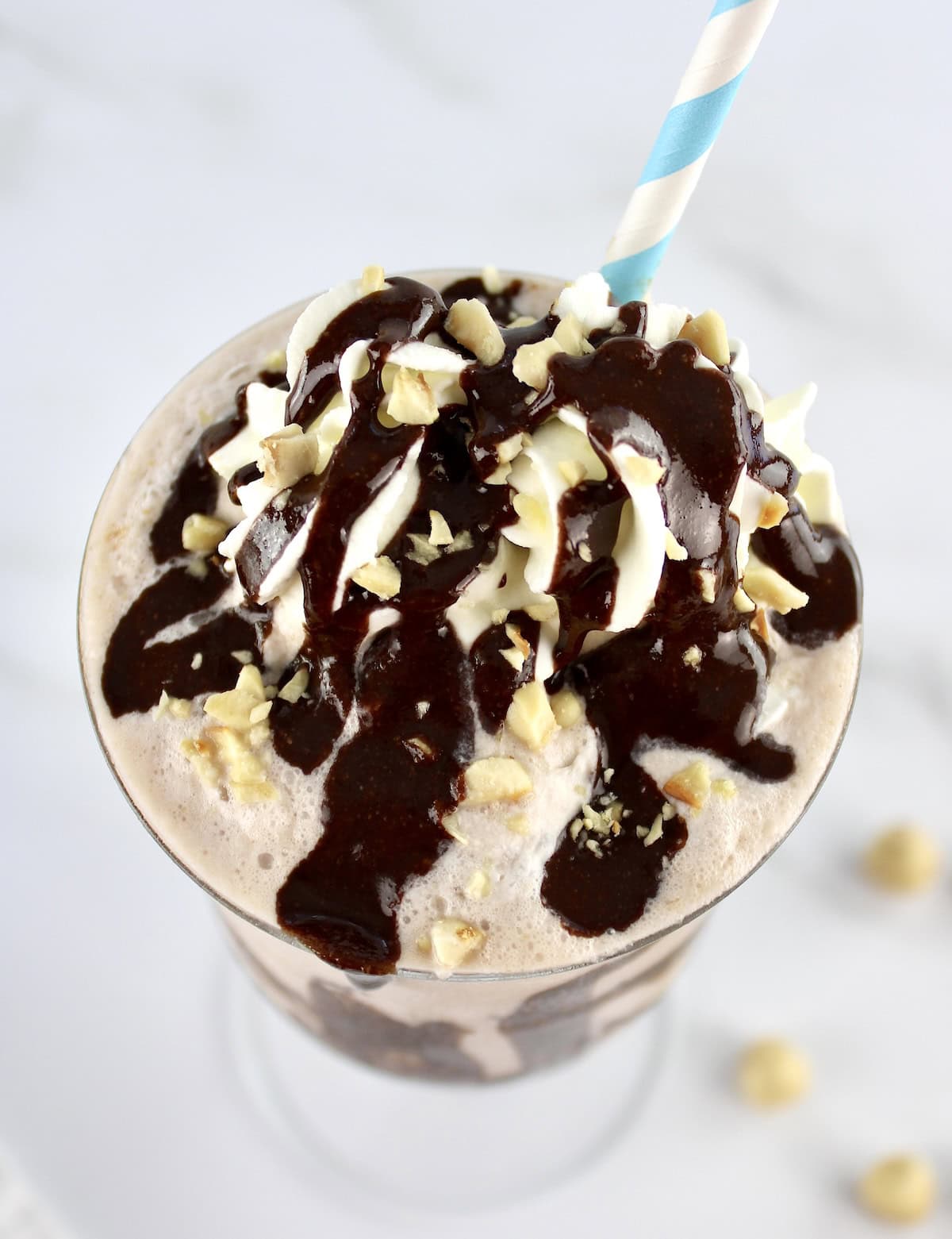 overhead view of top of Sugar-Free Nutella Protein Shake in glass with blue and white striped straw