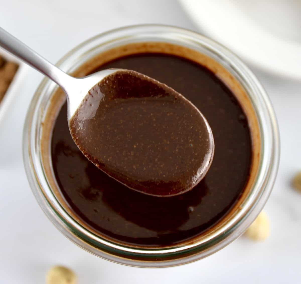 closeup of Sugar-Free Nutella in spoon held up over open jar