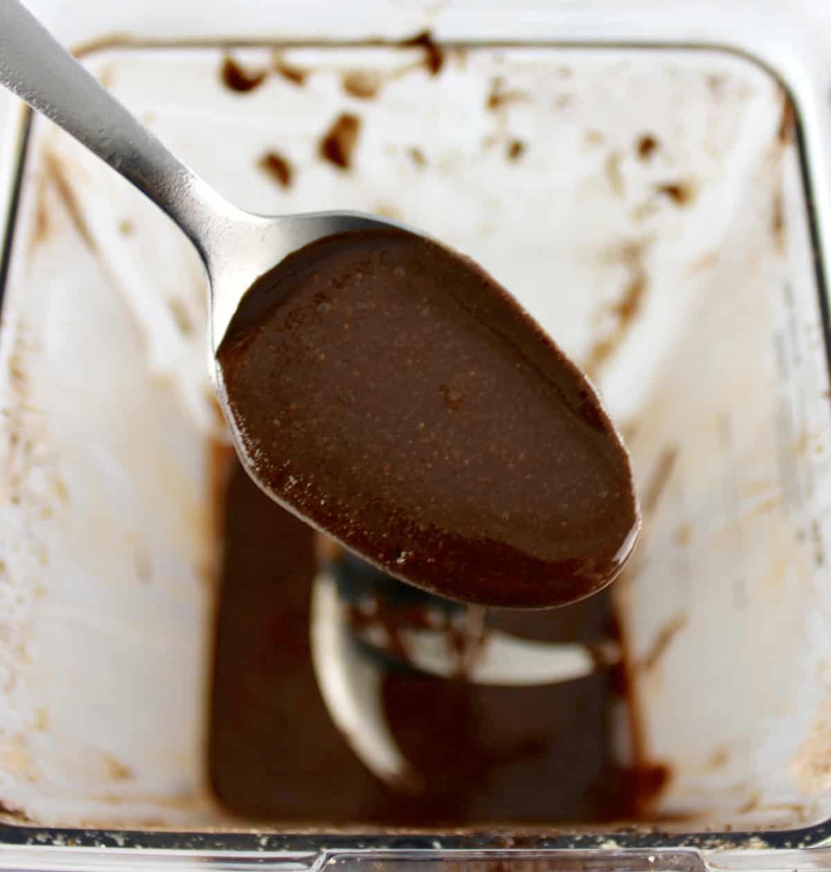 Sugar-Free Nutella with spoon holding up some over blender bowl