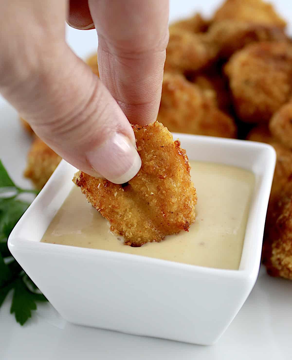 dipping Air Fryer Chicken Nugget in honey mustard sauce in white cup