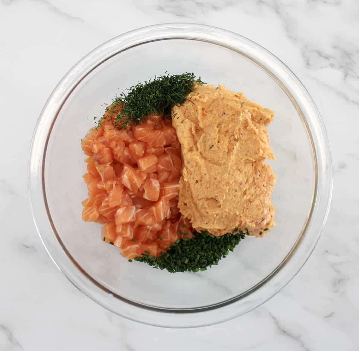 Boom Boom Salmon Burger ingredients with chopped dill and chopped salmon in glass bowl