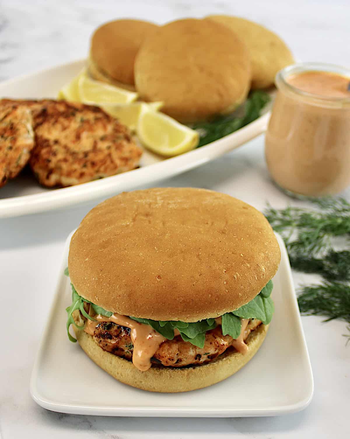 overhead view of Boom Boom Salmon Burger on bun with more burgers in back