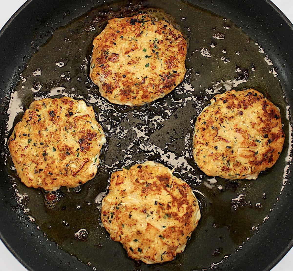 4 cooked Boom Boom Salmon Burger in skillet