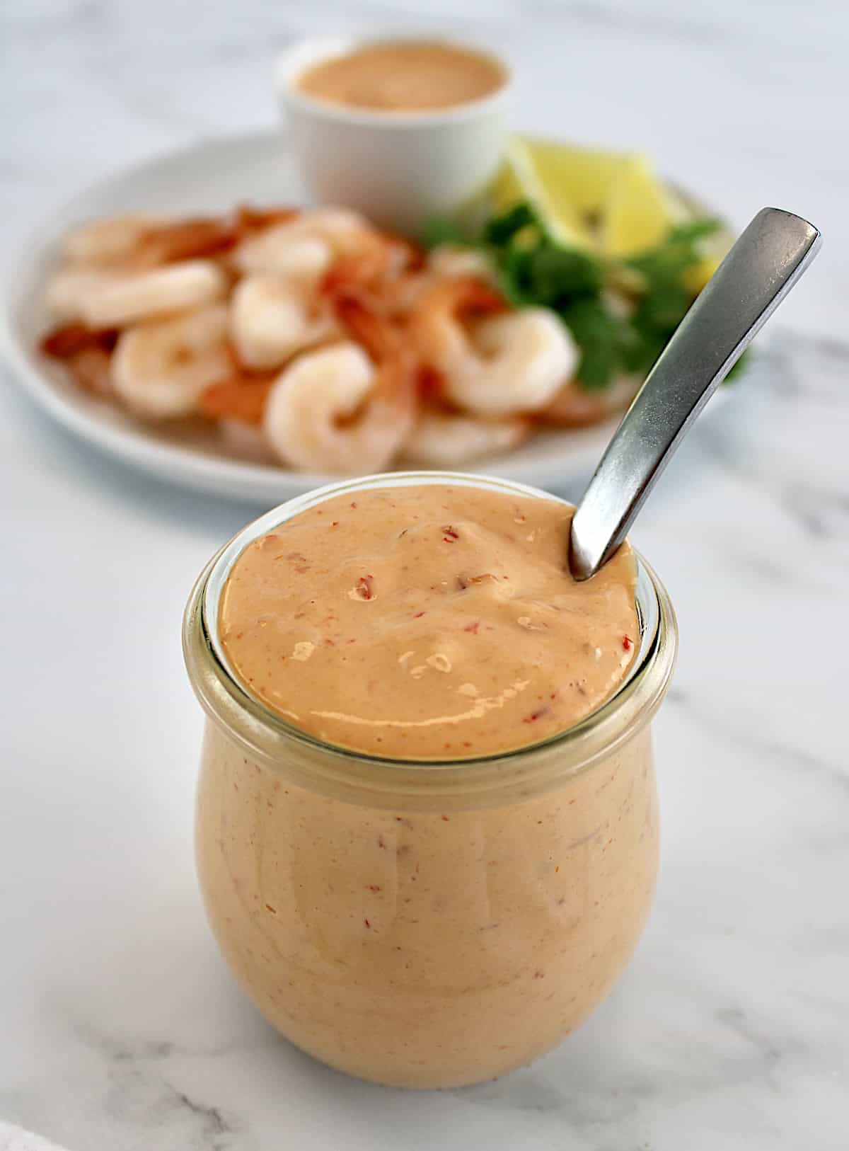 Boom Boom Sauce in open glass jar with spoon and shrimp in back