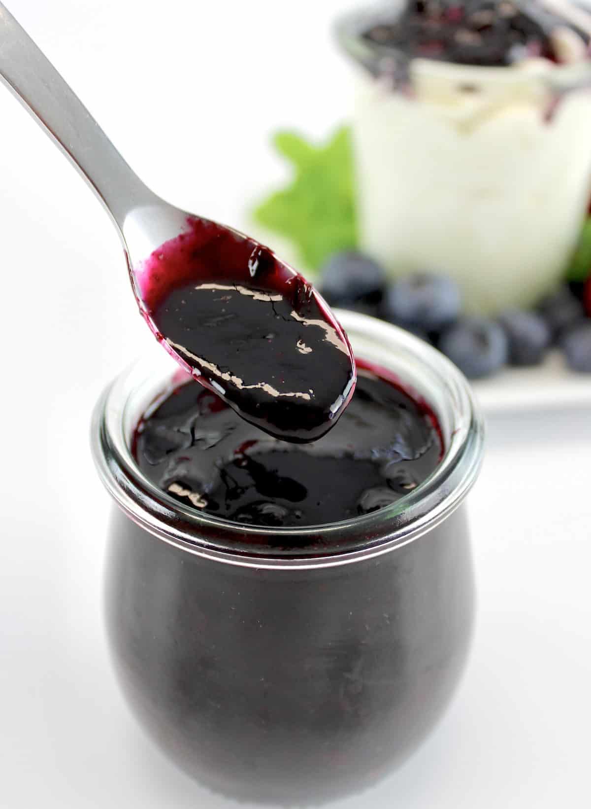 Keto Blueberry Sauce being spooned out of glass jar