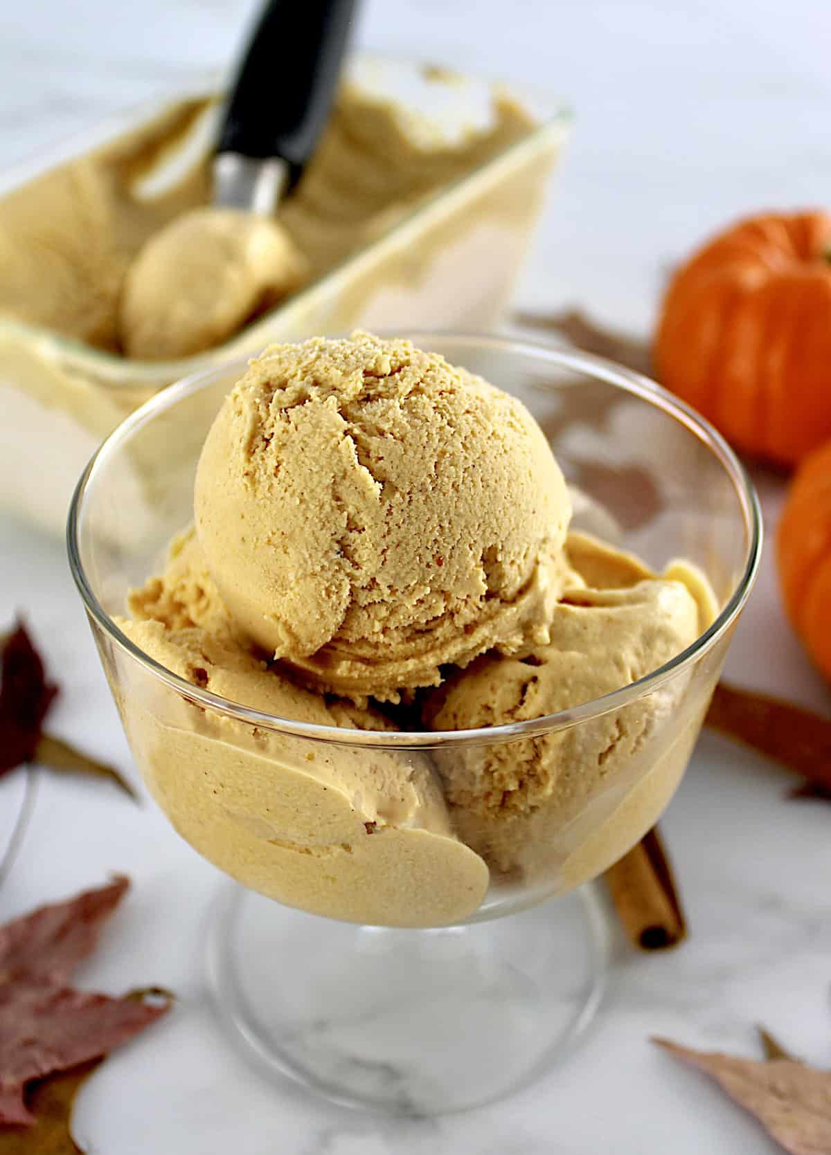 3 scoops of No-Churn Pumpkin Ice Cream in glass dish with more ice cream in back