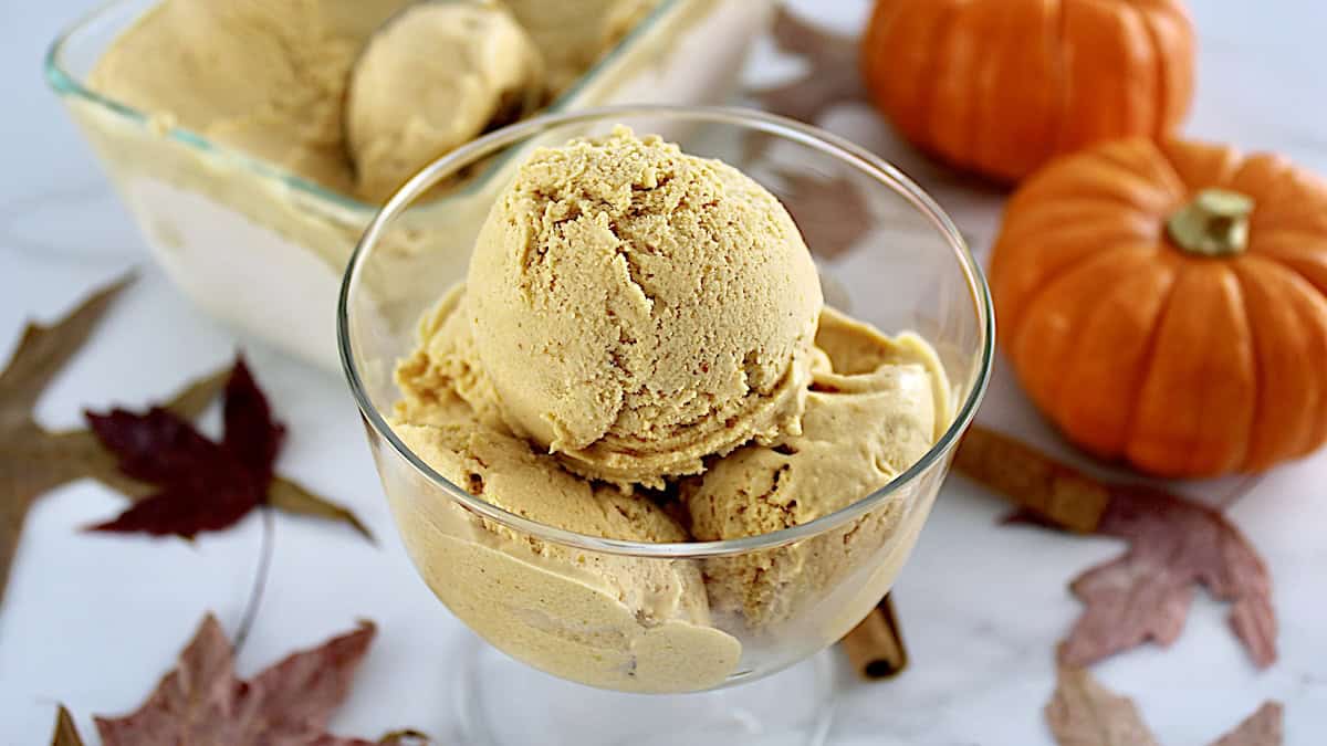 3 scoops of No-Churn Pumpkin Ice Cream in glass dish with more ice cream in back