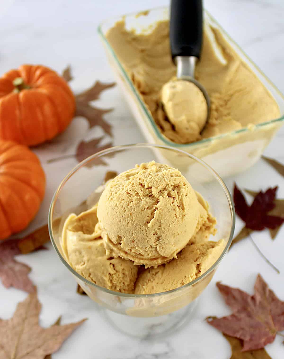 3 scoops of No-Churn Pumpkin Ice Cream in glass dish with more ice cream in back