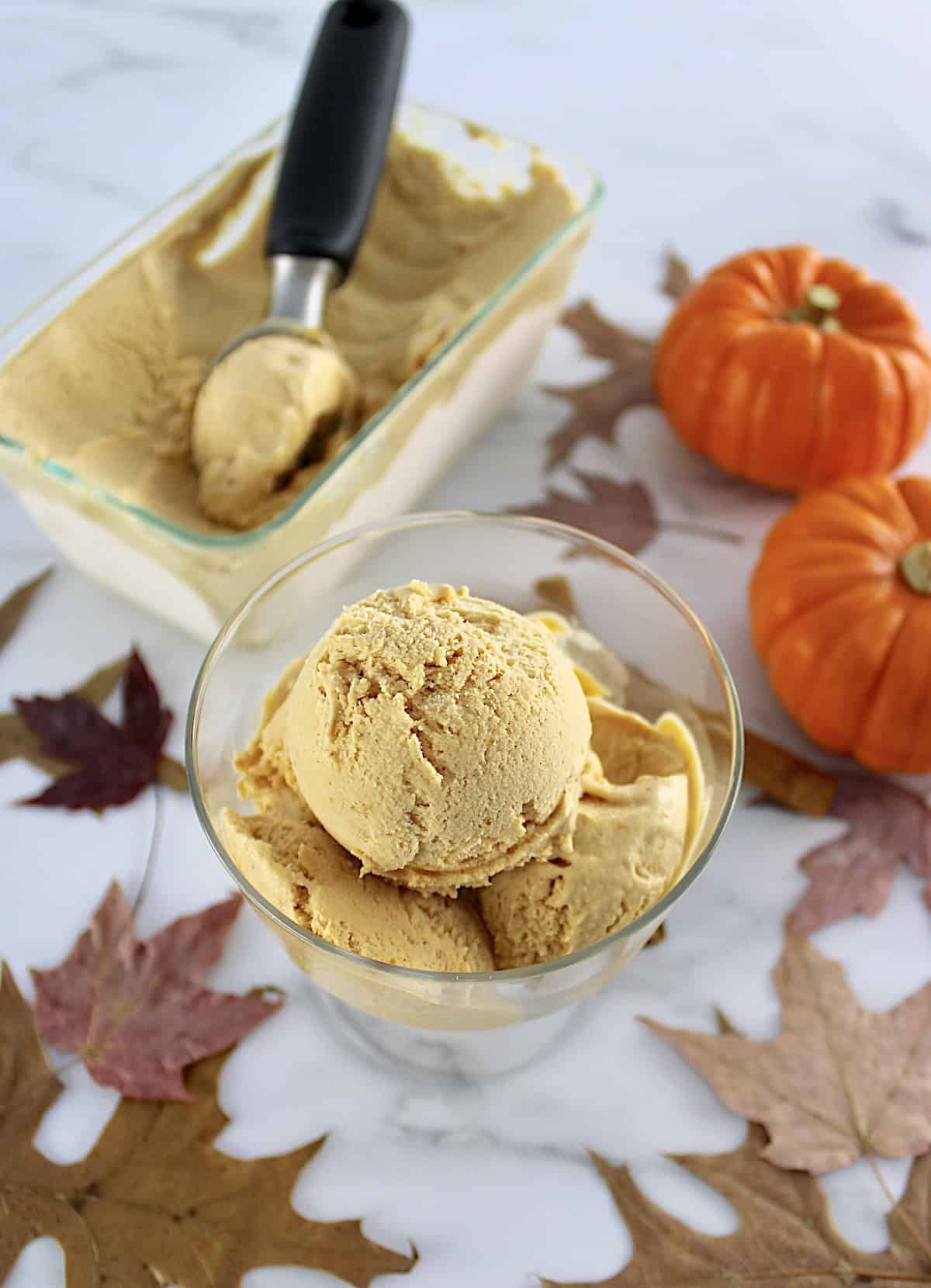 3 scoops of No-Churn Pumpkin Ice Cream in glass dish with more ice cream in back