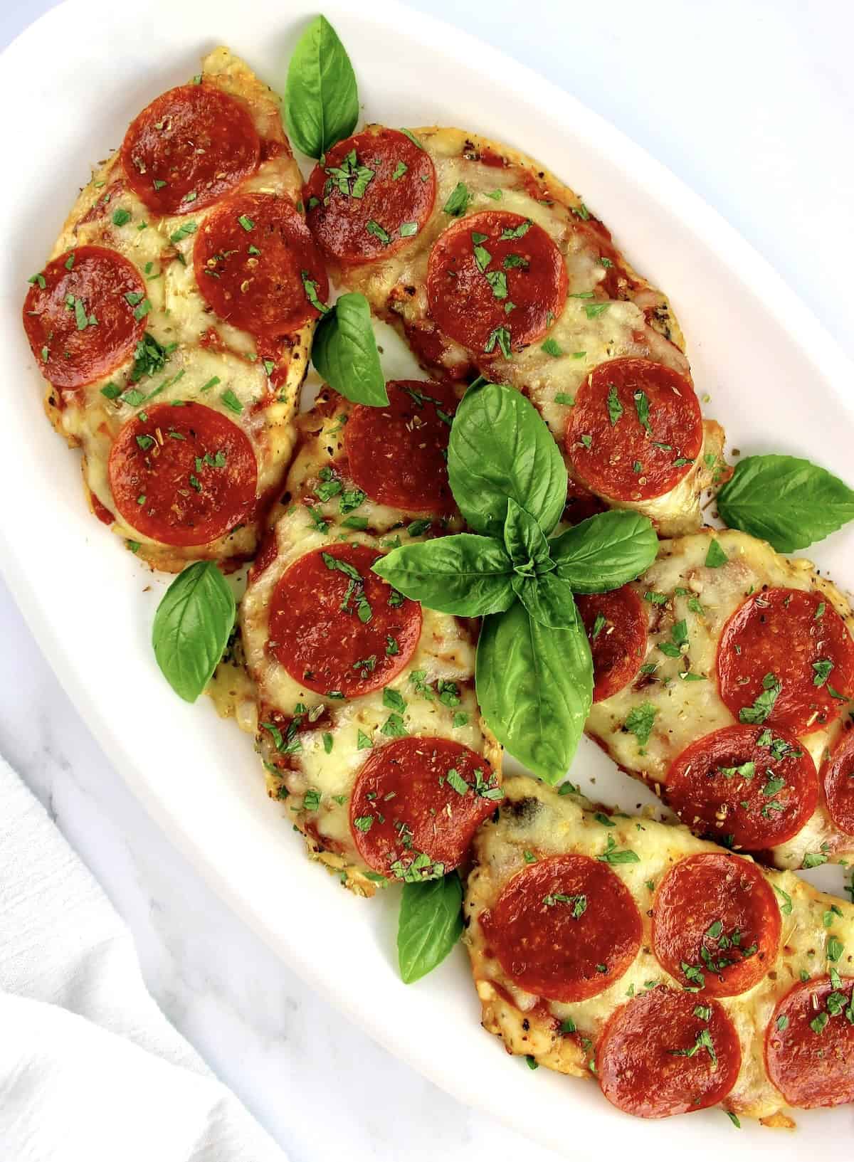 Pizza Chicken in white oval platter with fresh basil garnish