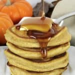 stack of Pumpkin Pancakes with pad of butter on top and maple syrup pouring over