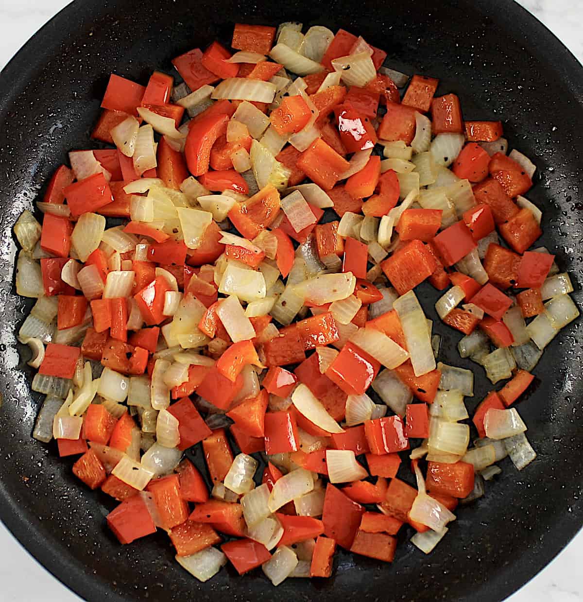 diced red bell peppers and onions in skillet cooked