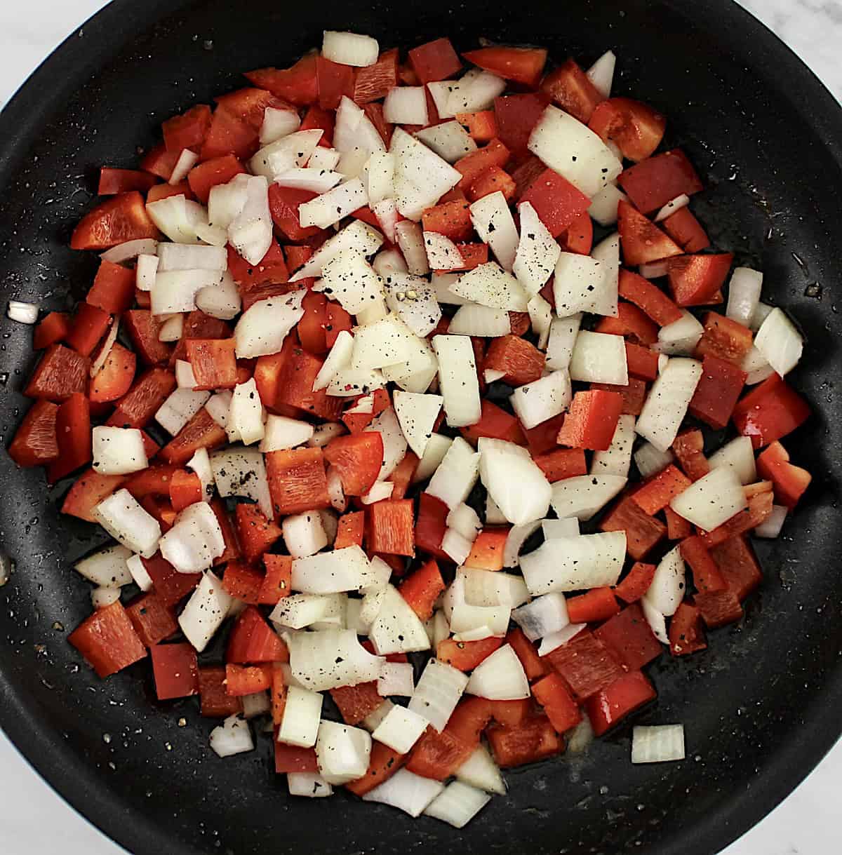 diced red bell peppers and onions in skillet uncooked