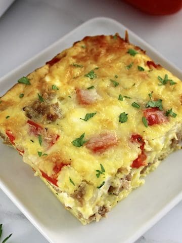 closeup of slice of Sausage and Peppers Breakfast Casserole on white square plate