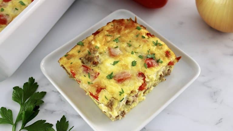 closeup of slice of Sausage and Peppers Breakfast Casserole on white square plate