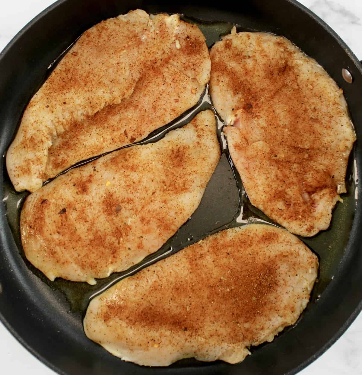 4 taco seasoned  raw chicken breasts in skillet