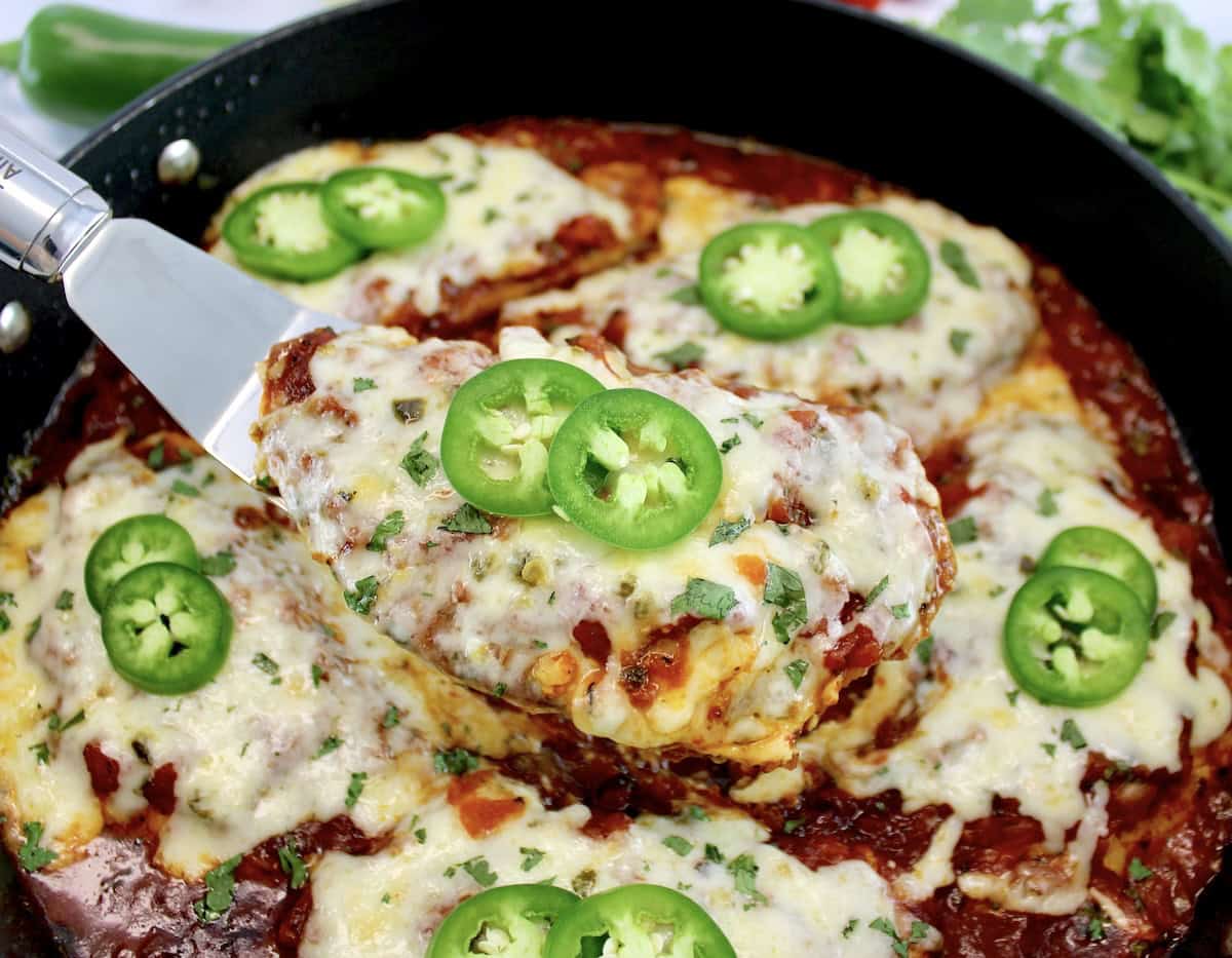 Skillet Salsa Chicken in skillet being held up by silver spatula