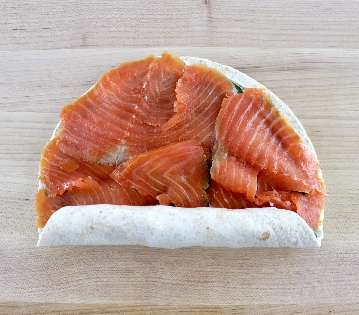 Smoked Salmon Pinwheel being rolled up on cutting board