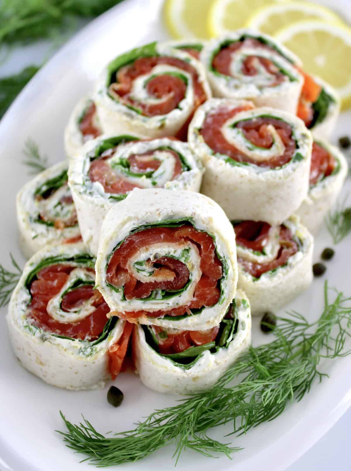 Smoked Salmon Pinwheels stacked up on white plate with one in front upright