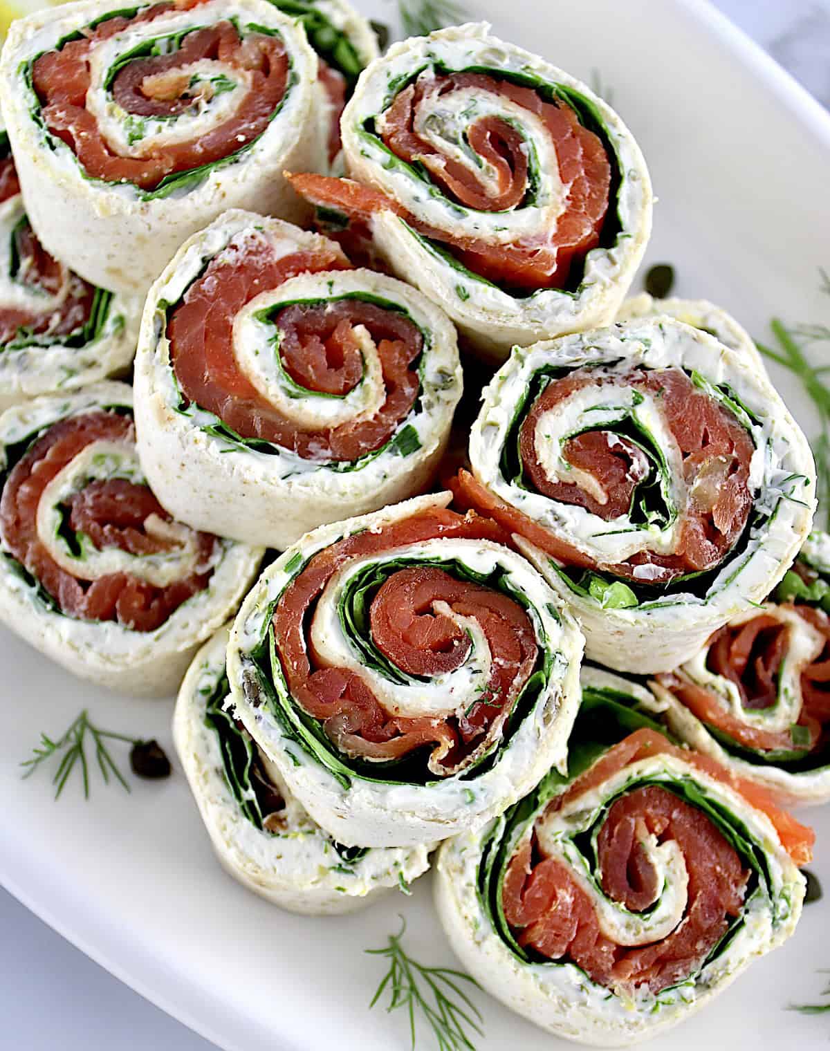 Smoked Salmon Pinwheels stacked up on white plate