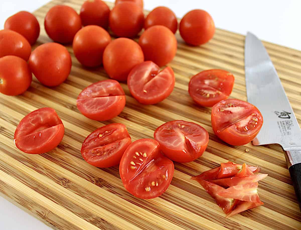 Campari tomatoes cut in half on cutting board with cores removed