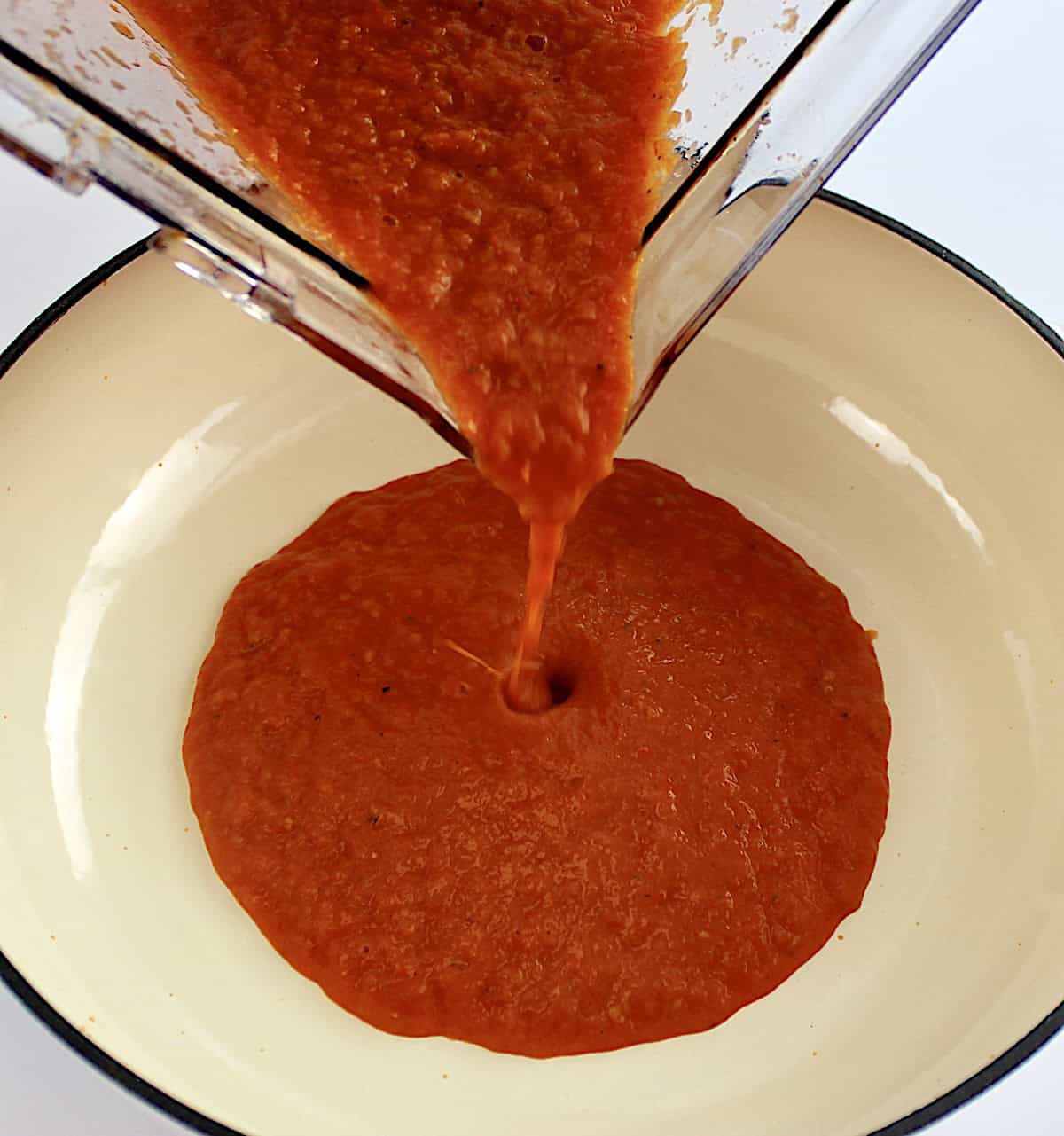 pureed roasted tomatoes being poured from blender into dutch oven