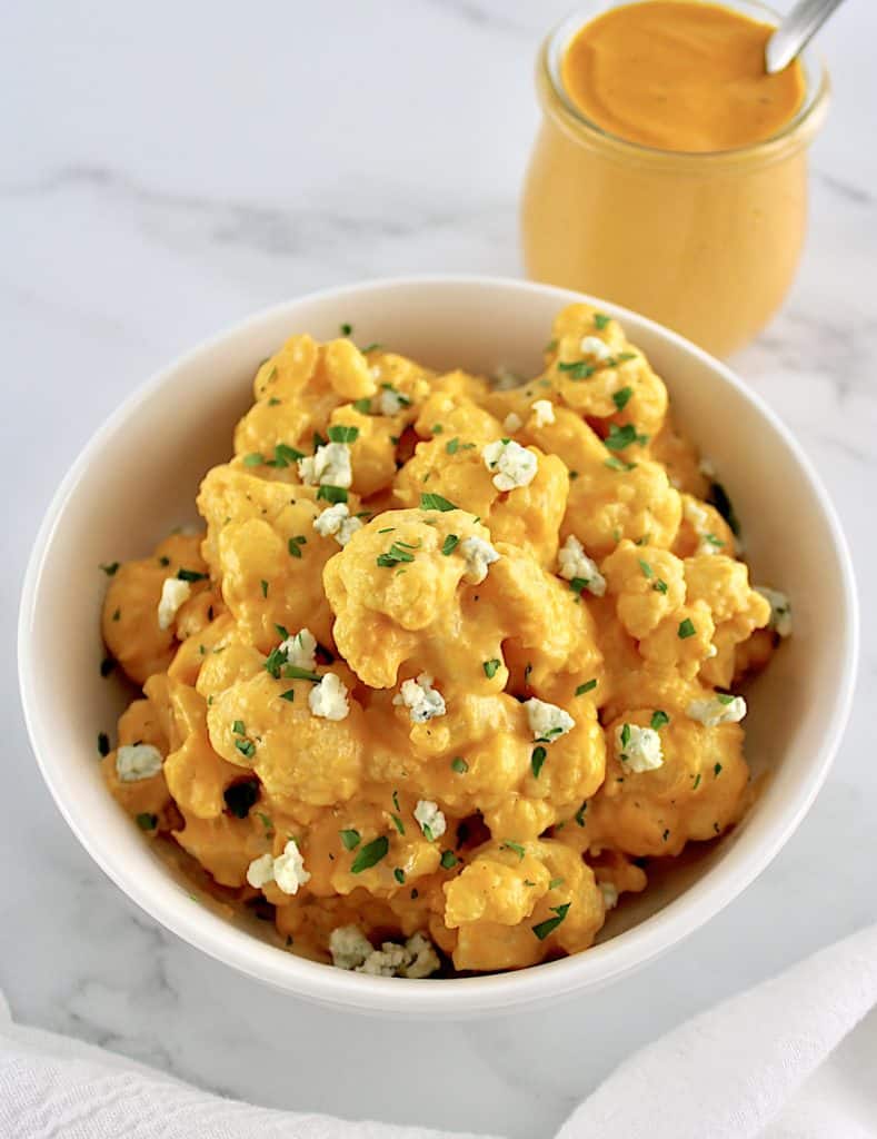 Buffalo Cauliflower Mac and Cheese in white bowl with sauce in back