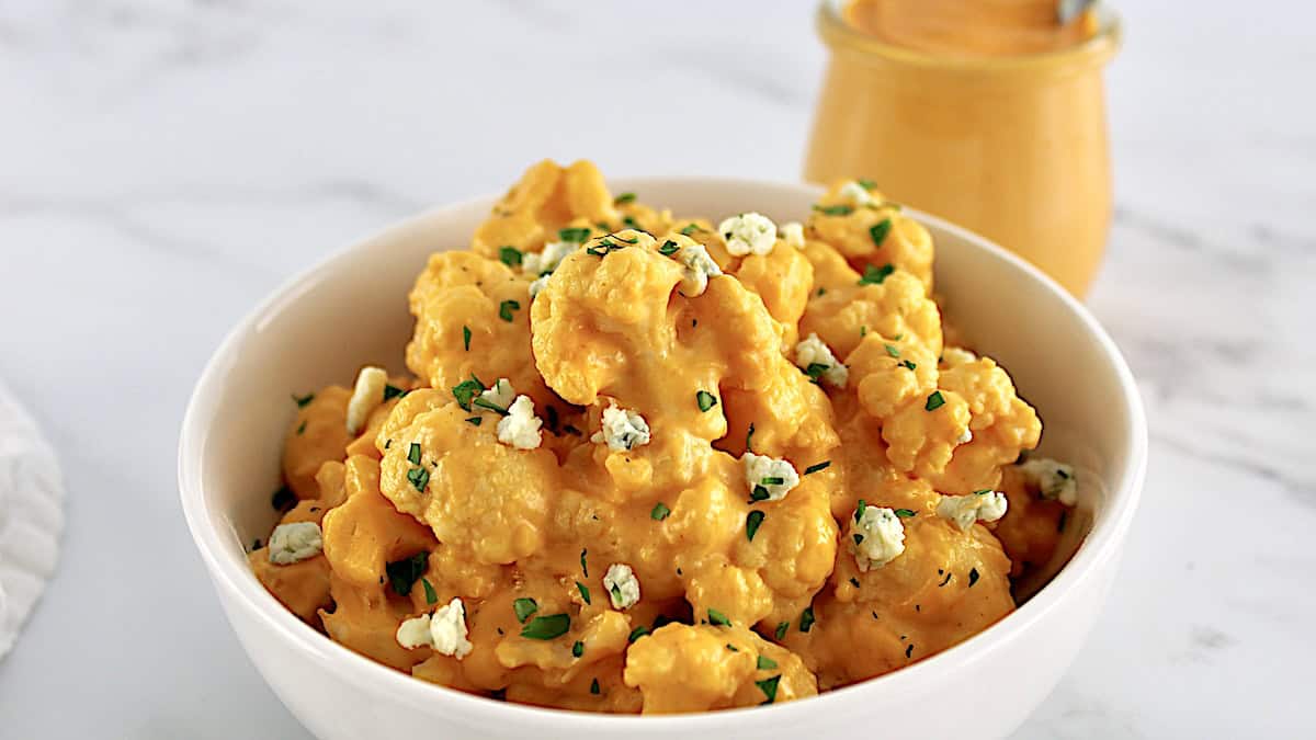 Buffalo Cauliflower Mac and Cheese in white bowl with blue cheese crumbles