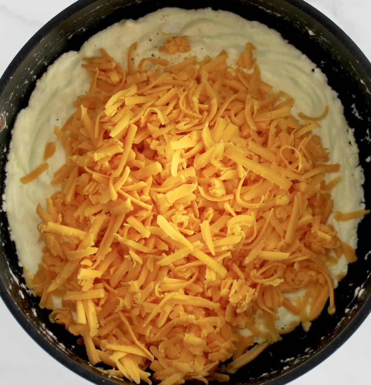 Buffalo Cheese Sauce and Dip ingredients with shredded cheddar in saucepan