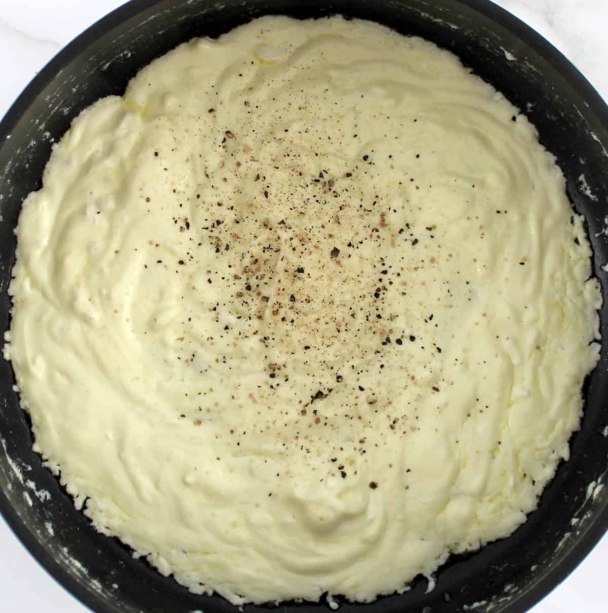 cheese sauce with salt and pepper in saucepan