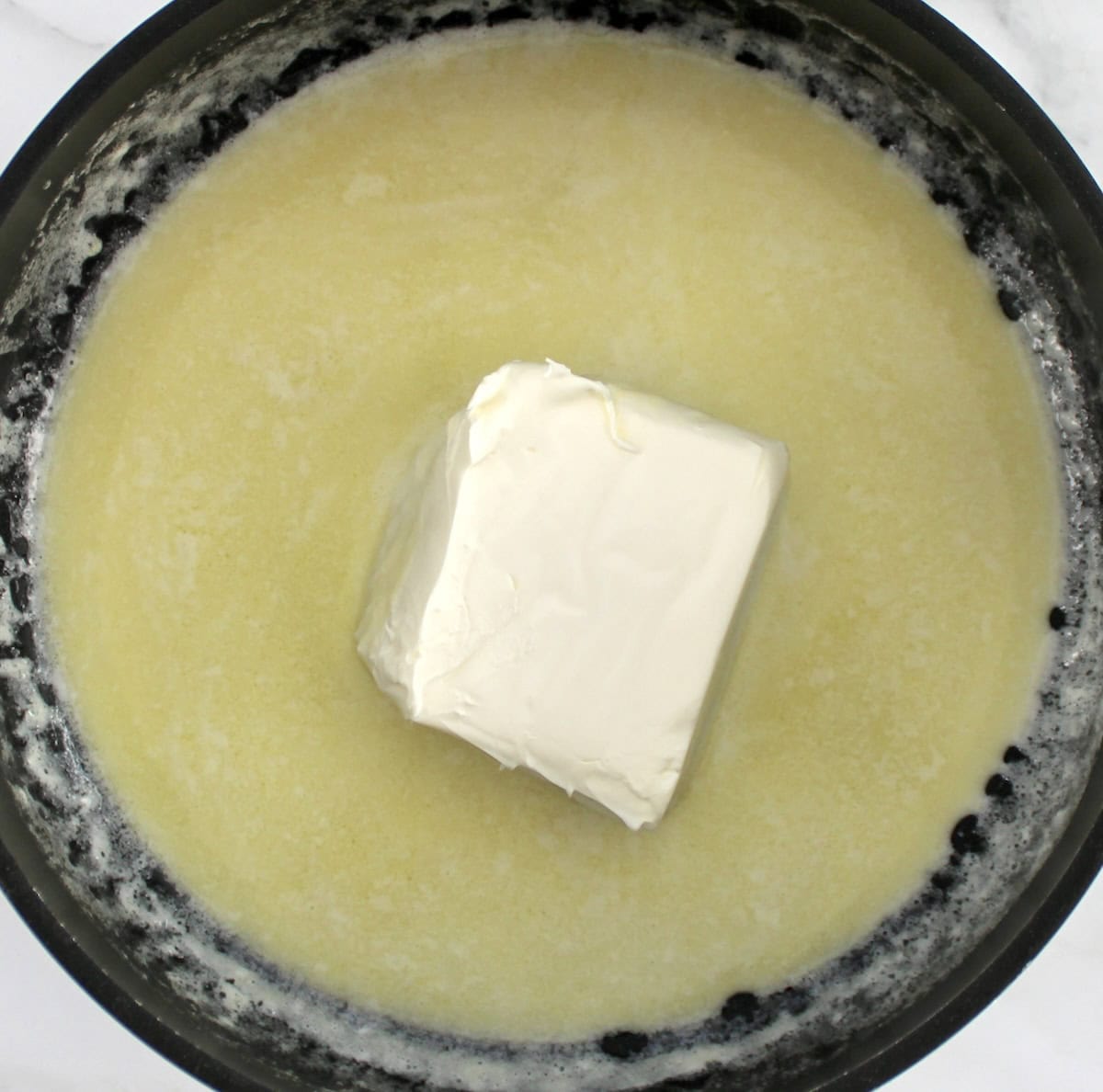 melted butter and cream with cream cheese block in saucepan