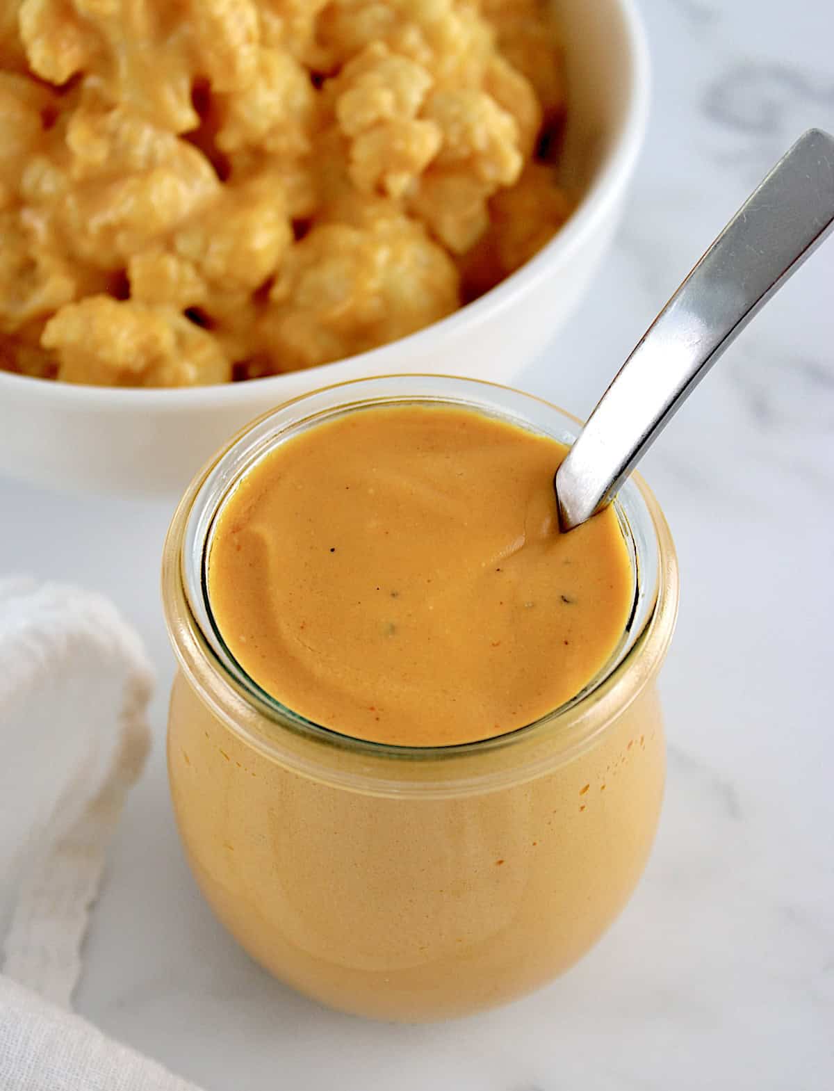 Buffalo Cheese Sauce and Dip in glass jar with cauliflower in back