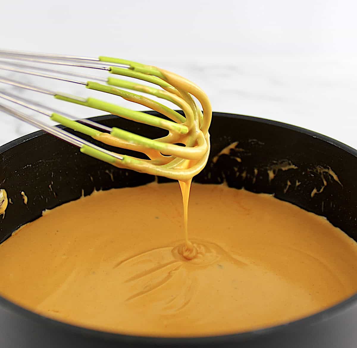 Buffalo Cheese Sauce and Dip in saucepan dripping off whisk