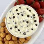 Cannoli Dip in white bowl with cookies and strawberries on side