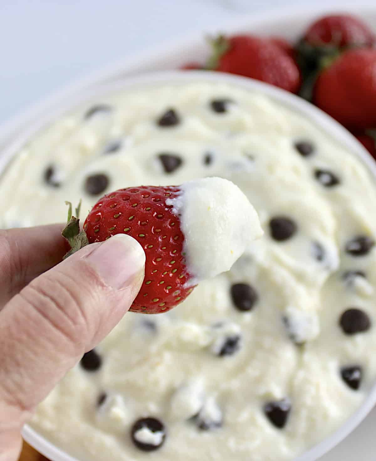 Cannoli Dip with strawberry being held up with dip