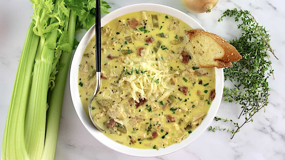 Chicken Cordon Bleu Soup in white bowl with spoon and bread on side