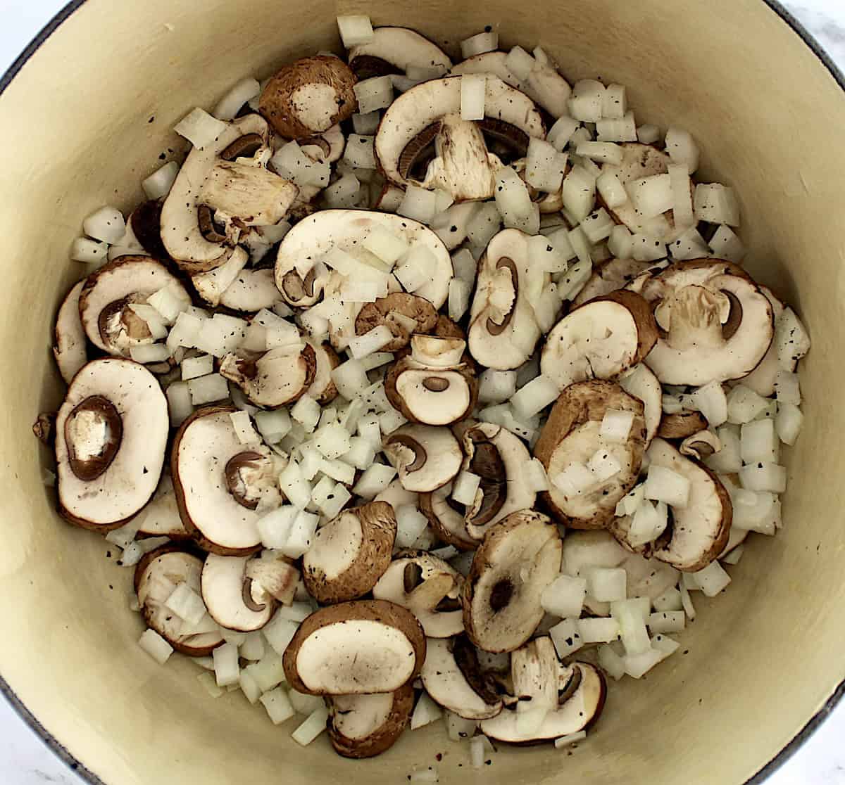 sliced mushrooms and diced onions cooking in pot