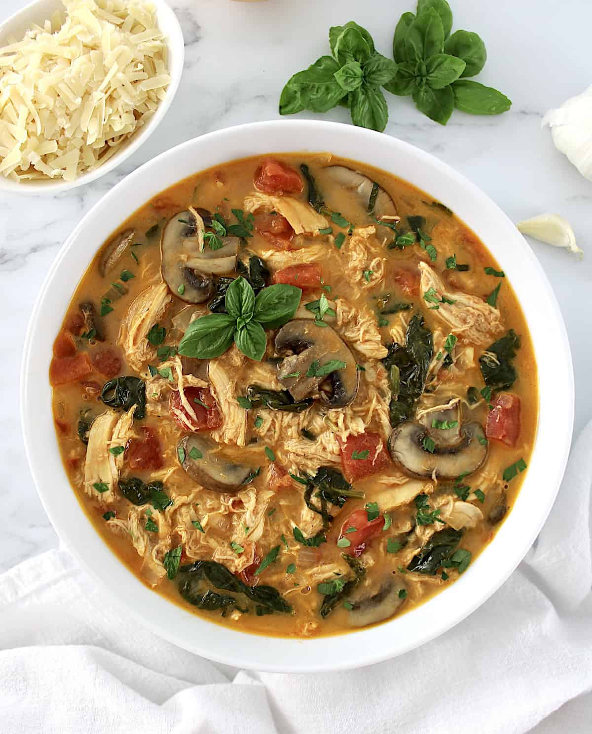 Tuscan Chicken Soup in white bowl with fresh basil garnish on top