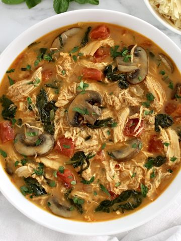 Tuscan Chicken Soup in white bowl with fresh basil garnish on top