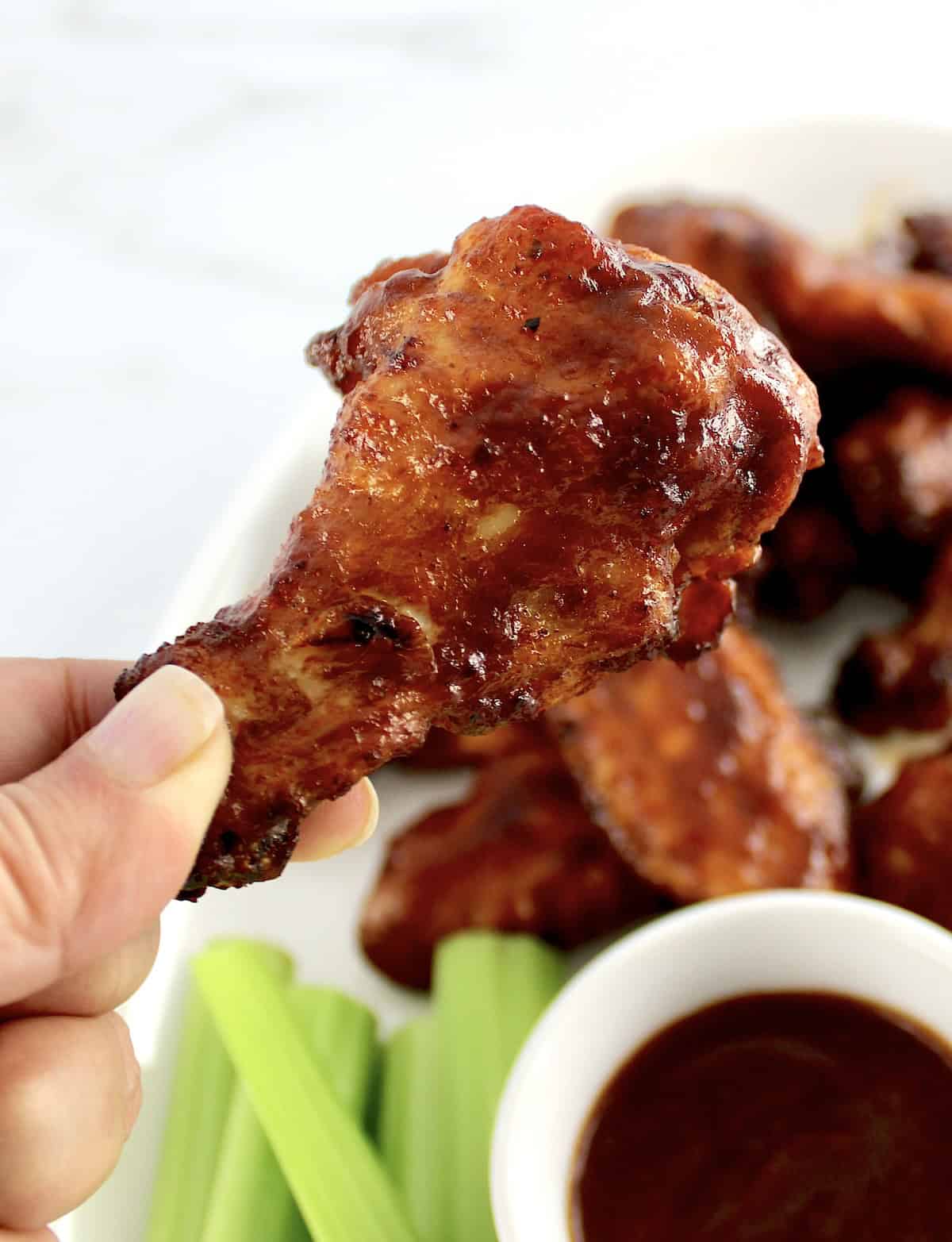 closeup of hand holding up Honey BBQ Chicken Wing