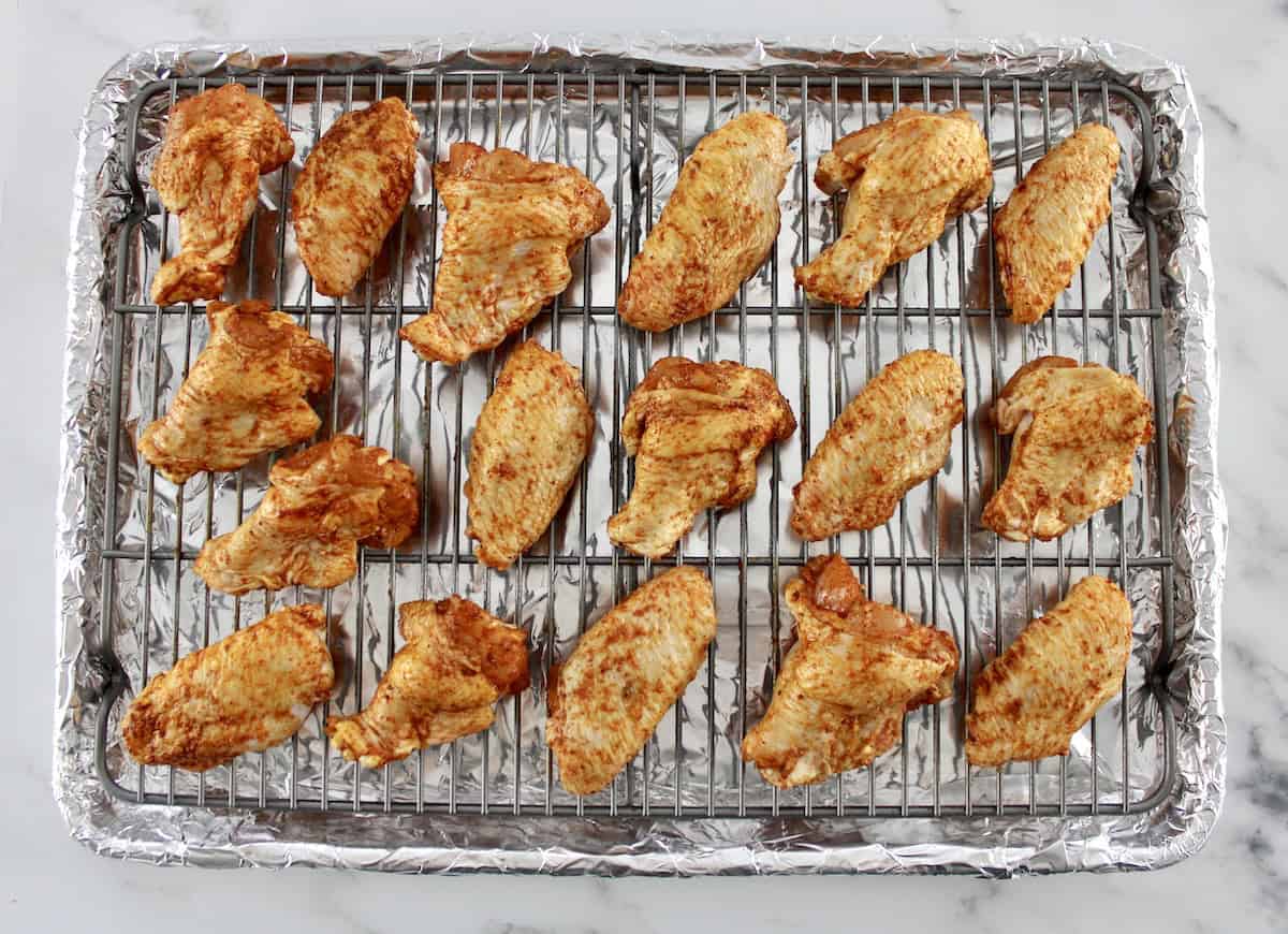 raw chicken wings on baking sheet with wire rack