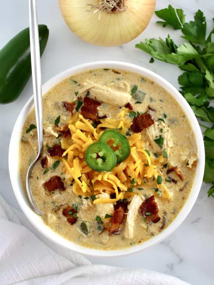 overhead view of Jalapeño Popper Chicken Soup in white bowl with spoon