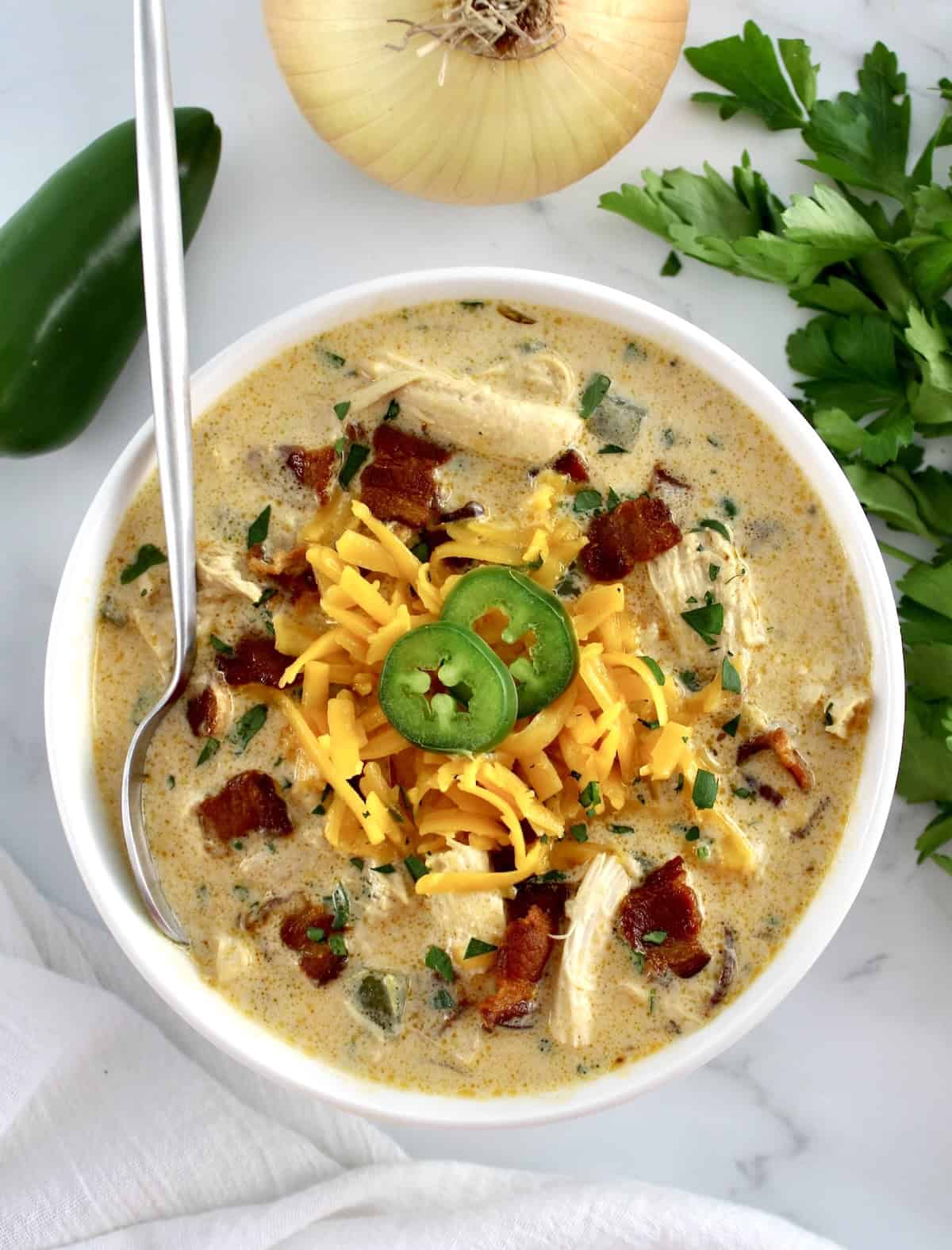 overhead view of Jalapeño Popper Chicken Soup in white bowl with spoon