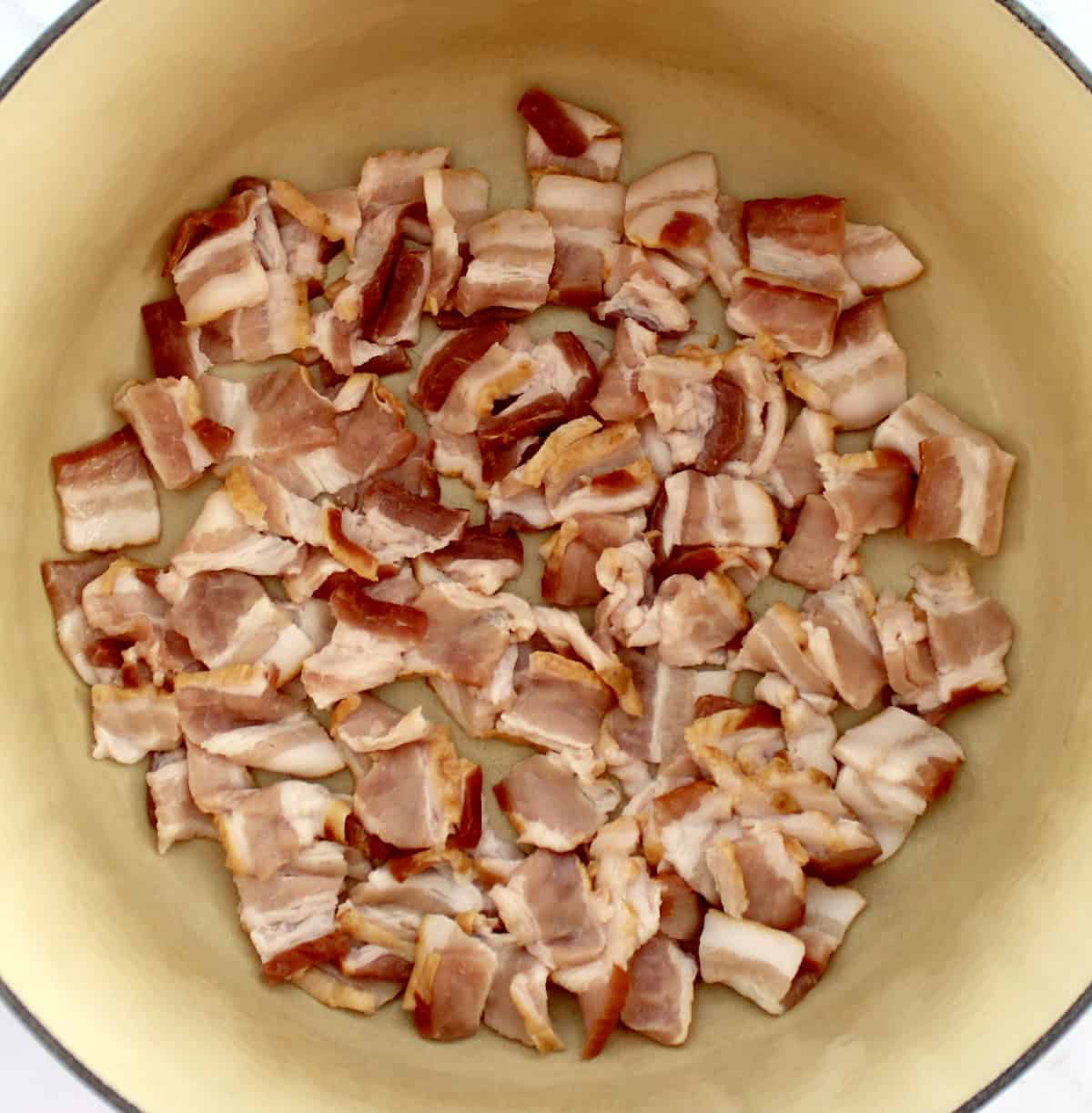 raw bacon pieces frying in pot