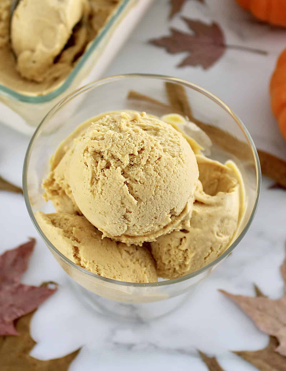 overhead view of 3 scoops of No-Churn Pumpkin Ice Cream in glass dish with more ice cream in back