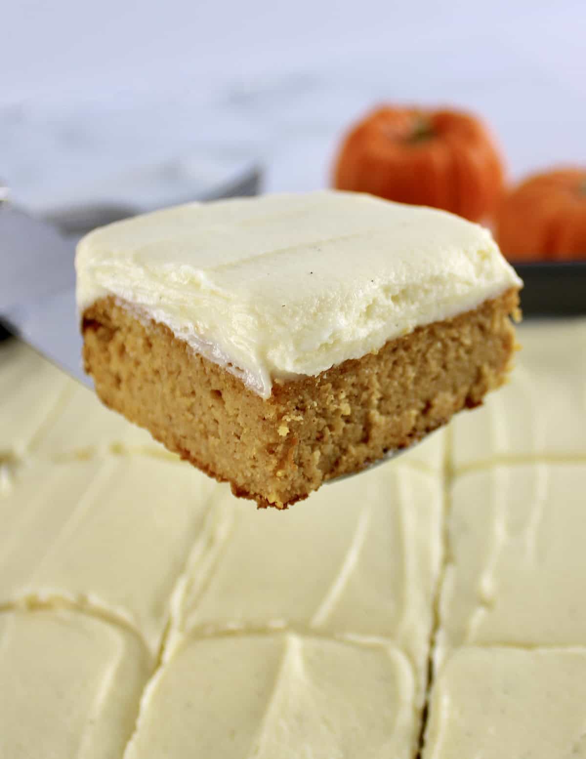 spatula holding up slice of frosted Pumpkin Spice Cake