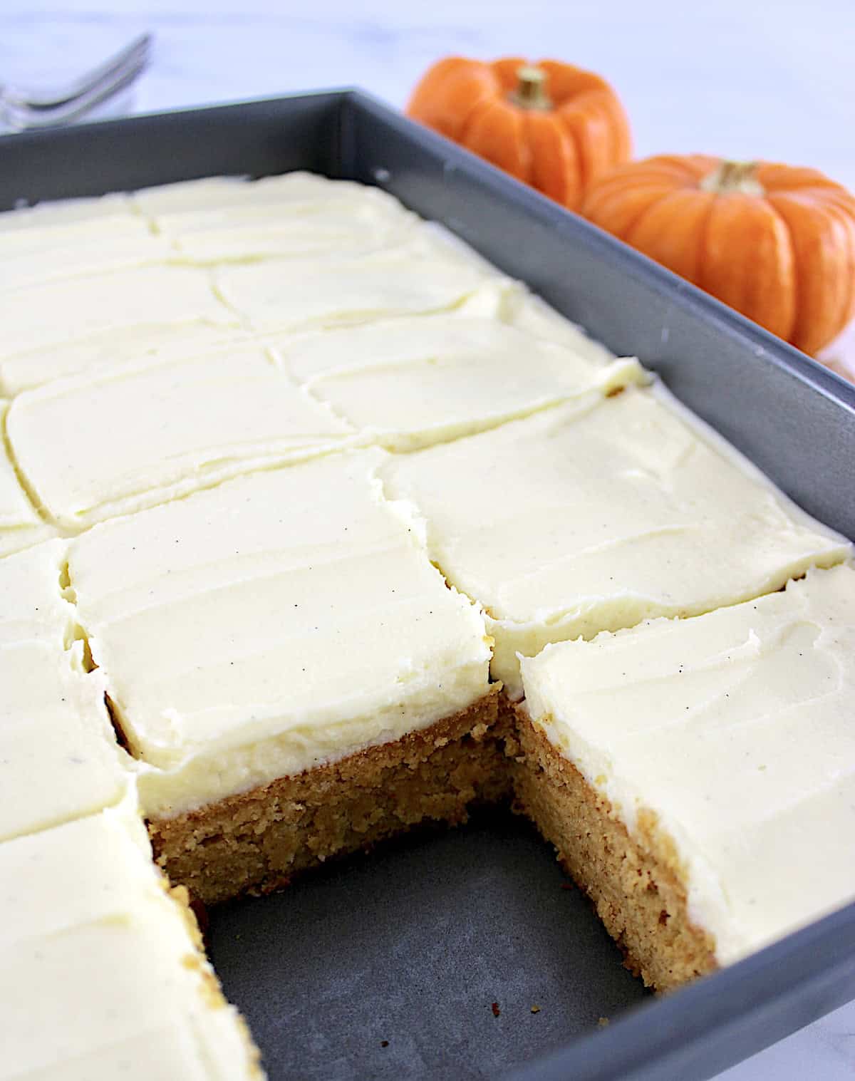 Pumpkin Spice Cake in baking pan cut into slices and frosted