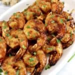 Air Fryer Asian Shrimp Skewers stacked up on white oval platter with chopped parsley on top