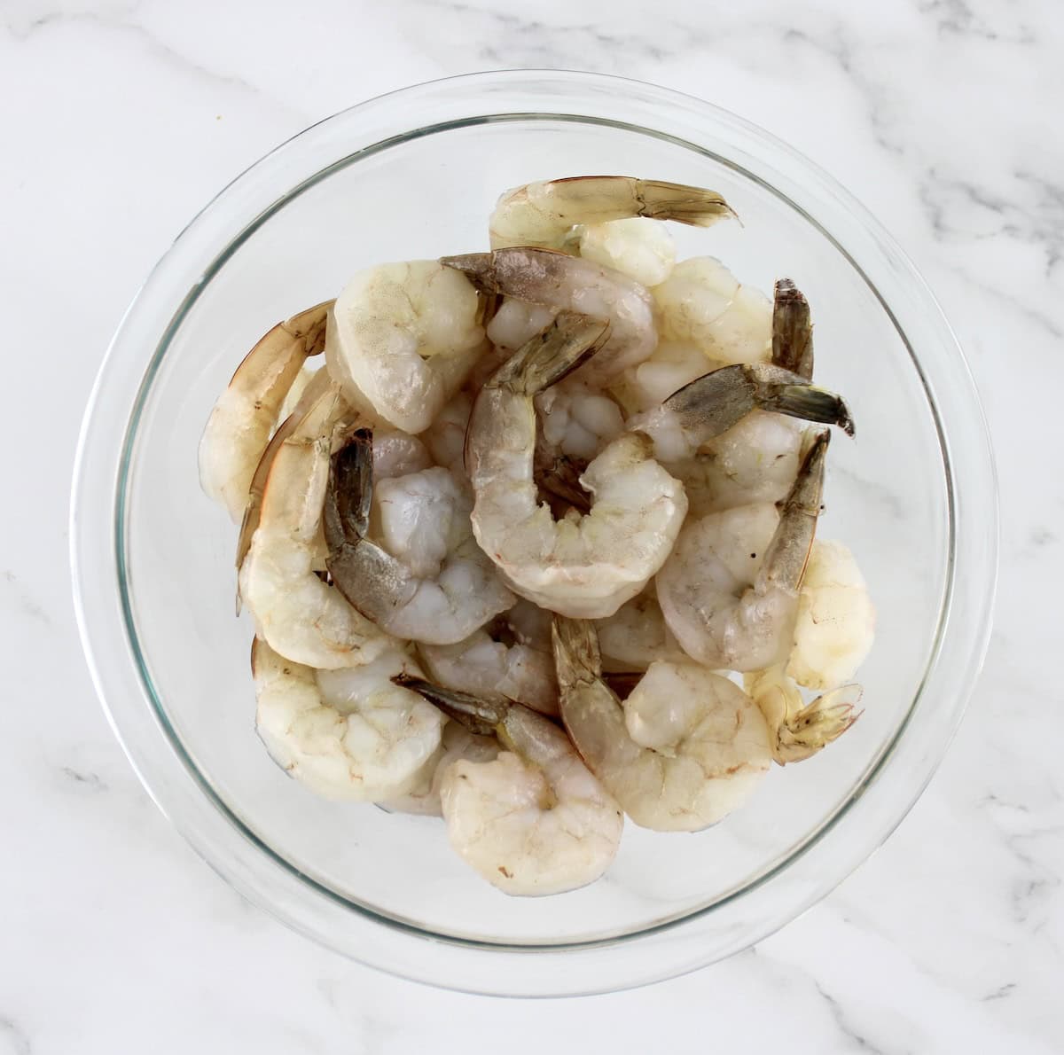 raw shrimp with tails on in glass bowl