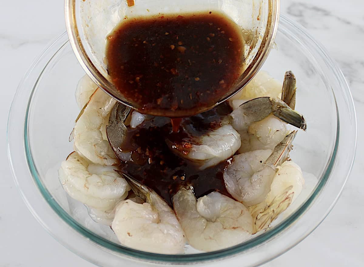 Air Fryer Asian Shrimp Skewers marinade being poured over raw shrimp in glass bowl